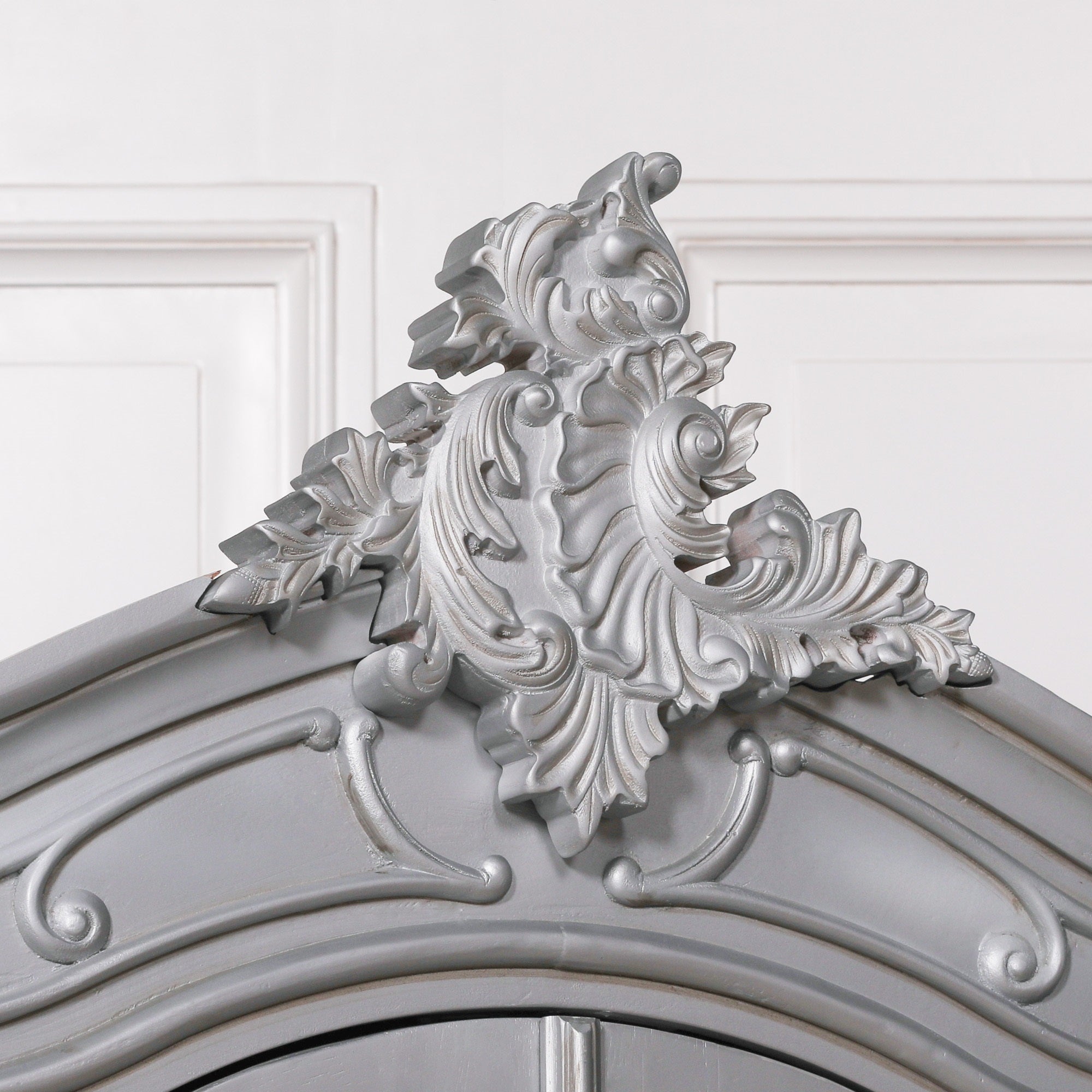 Detailed view of the Vivienne Silver Carved Mirrored Double Door Armoire Wardrobe highlighting the ornate Rococo crest, hand-carved floral scrollwork, decorative crown moulding and elegant silver finish.