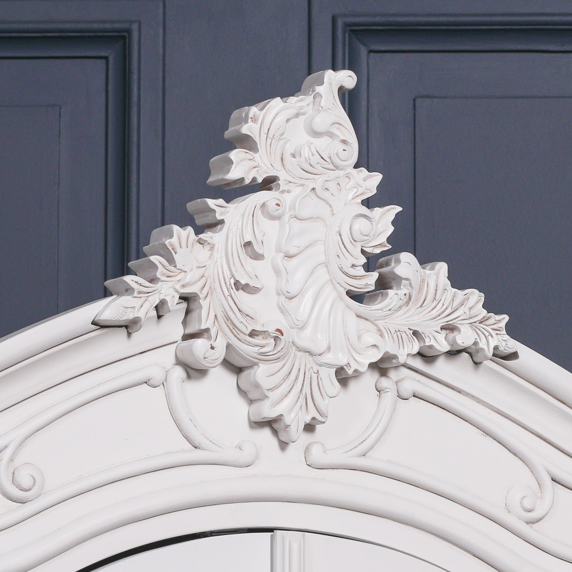 Detailed view of the Vivienne White Carved Mirrored Double Door Armoire Wardrobe highlighting the ornate Rococo crest, hand-carved floral scrollwork, decorative crown moulding and elegant painted white finish.