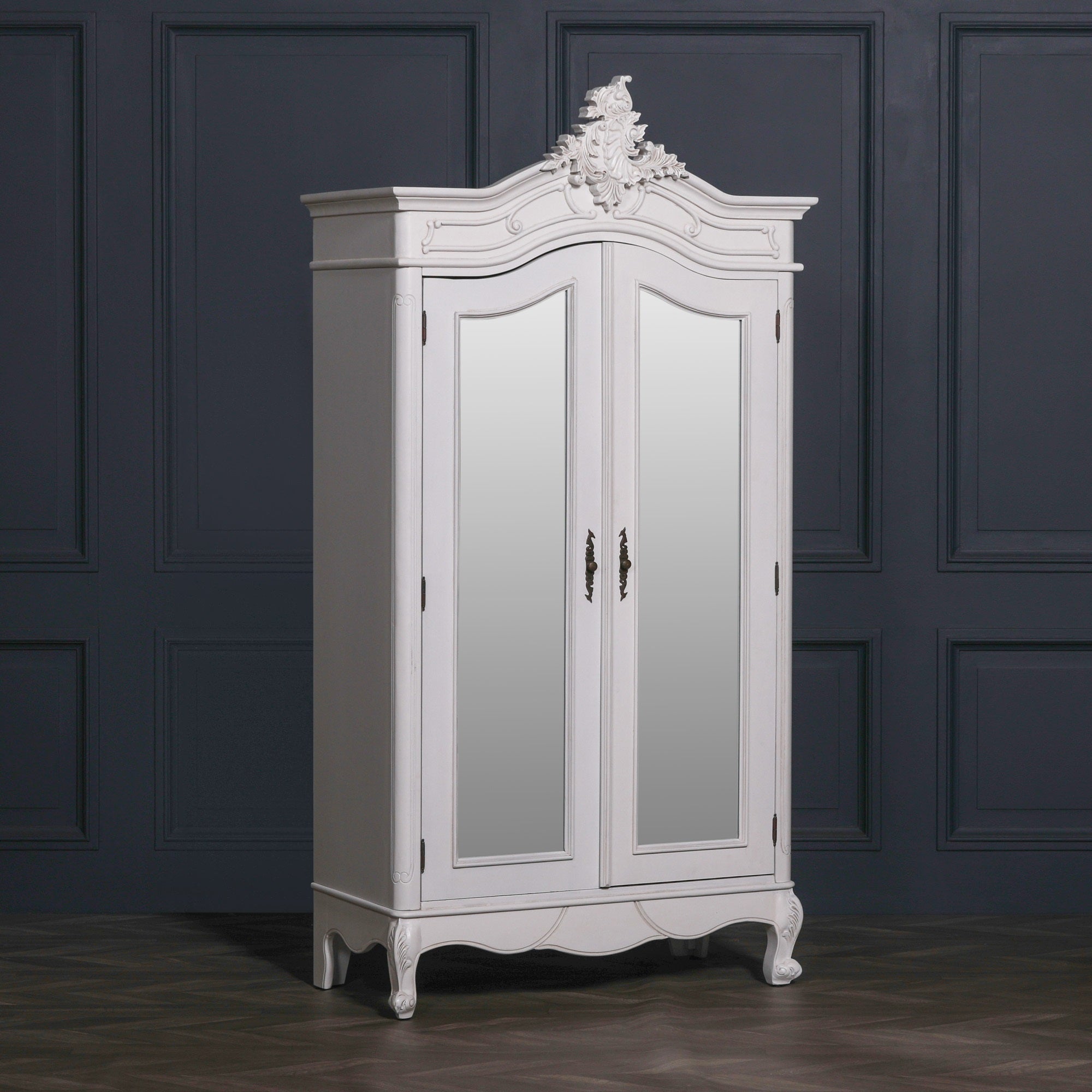 Vivienne White Carved Mirrored Double Door Armoire Wardrobe featuring elegant French Rococo styling, full-length mirrored doors, ornate hand-carved crown detailing, decorative cabriole feet and a painted white finish, displayed in a luxury bedroom interior.